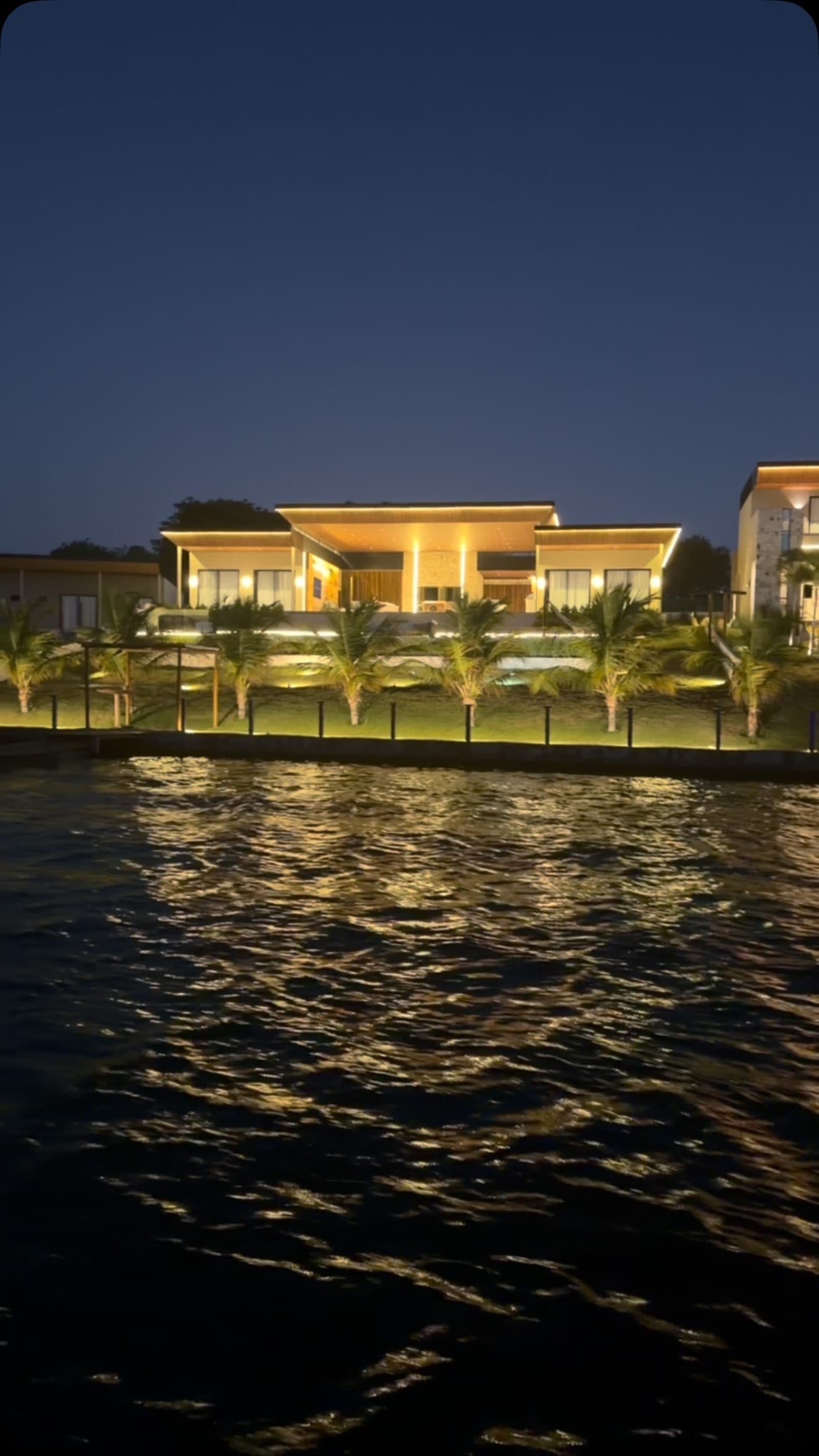 Casa iluminada às margens da lagoa, à noite